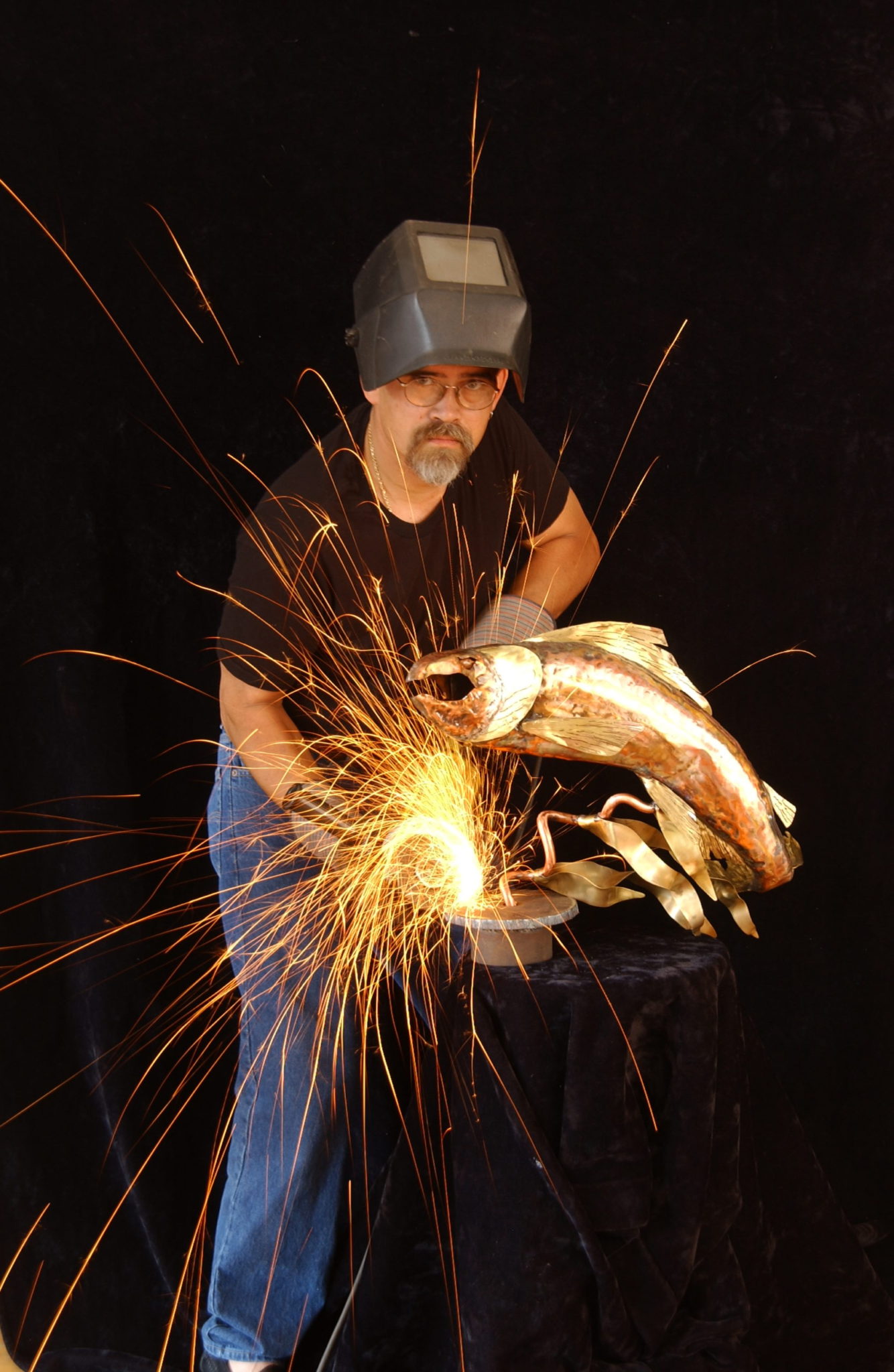 David Bosma grinding a metal fish sculpture, sparks flying